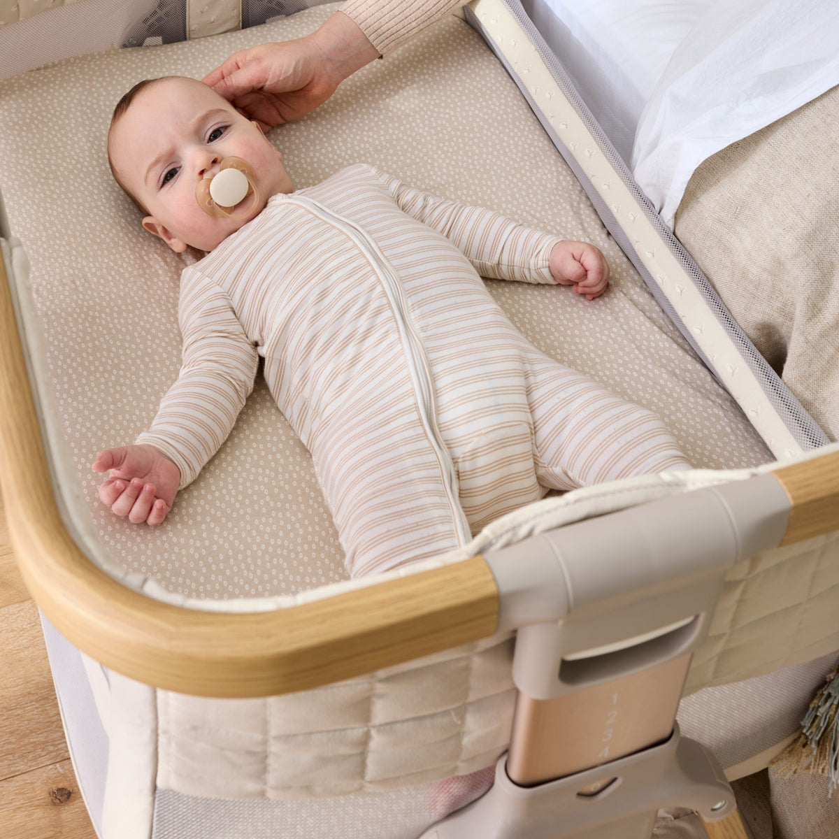 Baby with a dummy lying on their back in the CoZee Breeze Sense bassinet