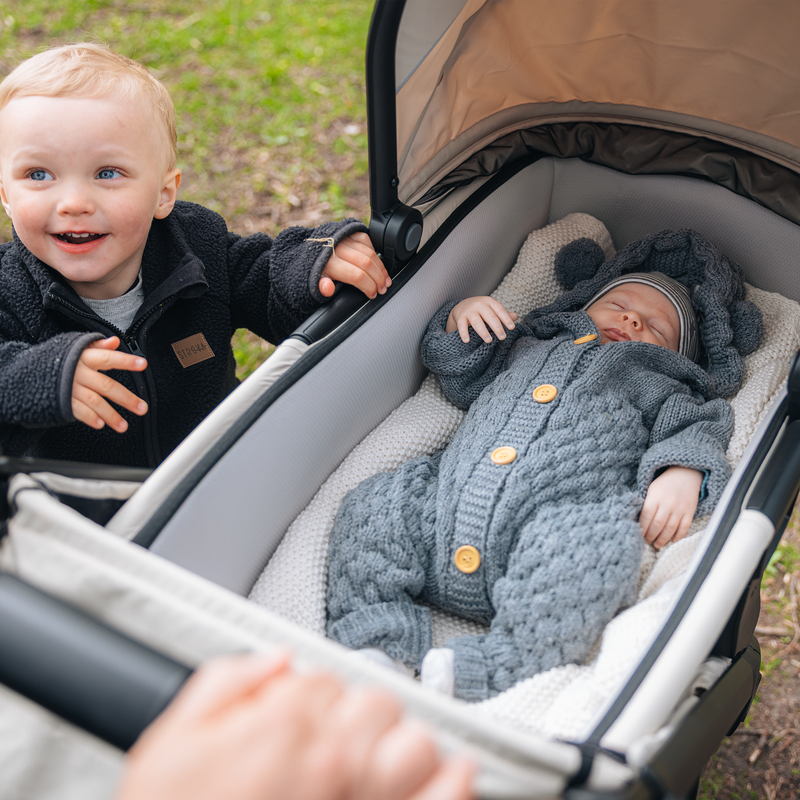 Newborn lying in the Thule Spring 2 bassinet with an older sibling nearby