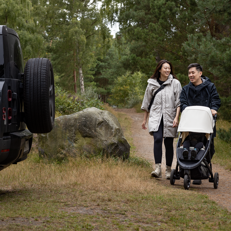 Couple walking with the Thule Spring 2 all-terrain stroller on a forest trail