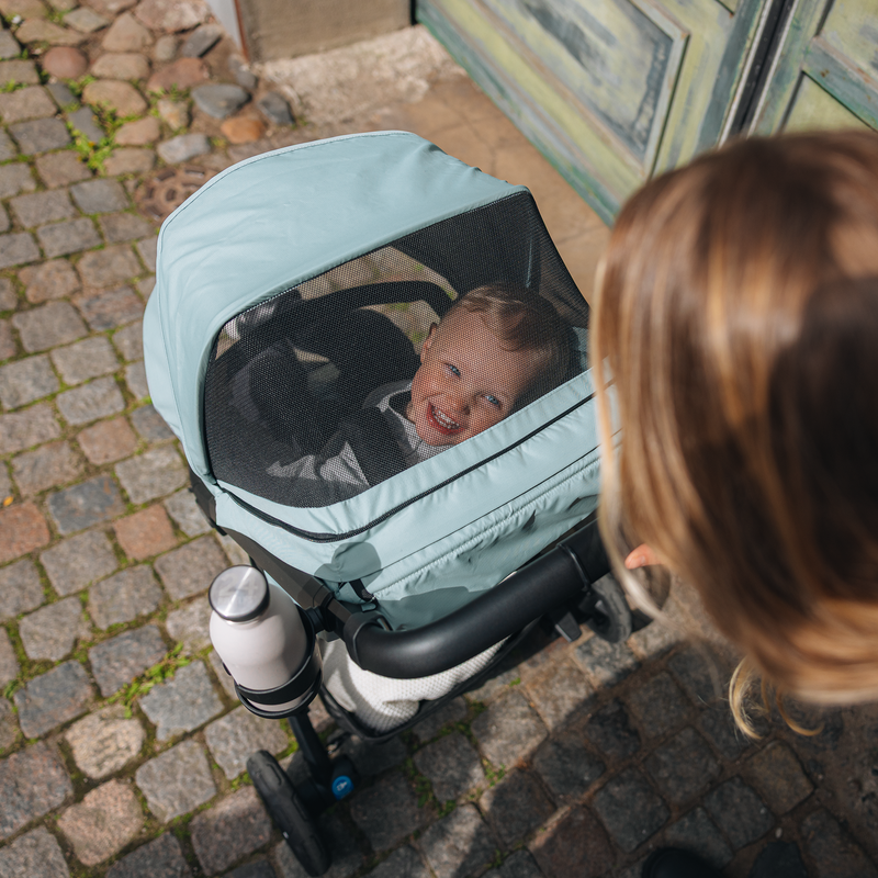 Child sleeping in the Thule Spring 2 bassinet with the mesh cover fitted