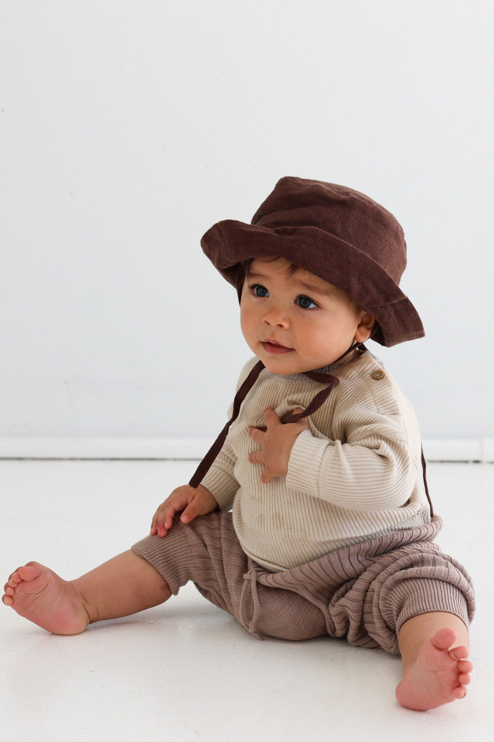 Baby wearing the Mumma Etcetera linen sun hat in Coco chocolate brown with neck tie