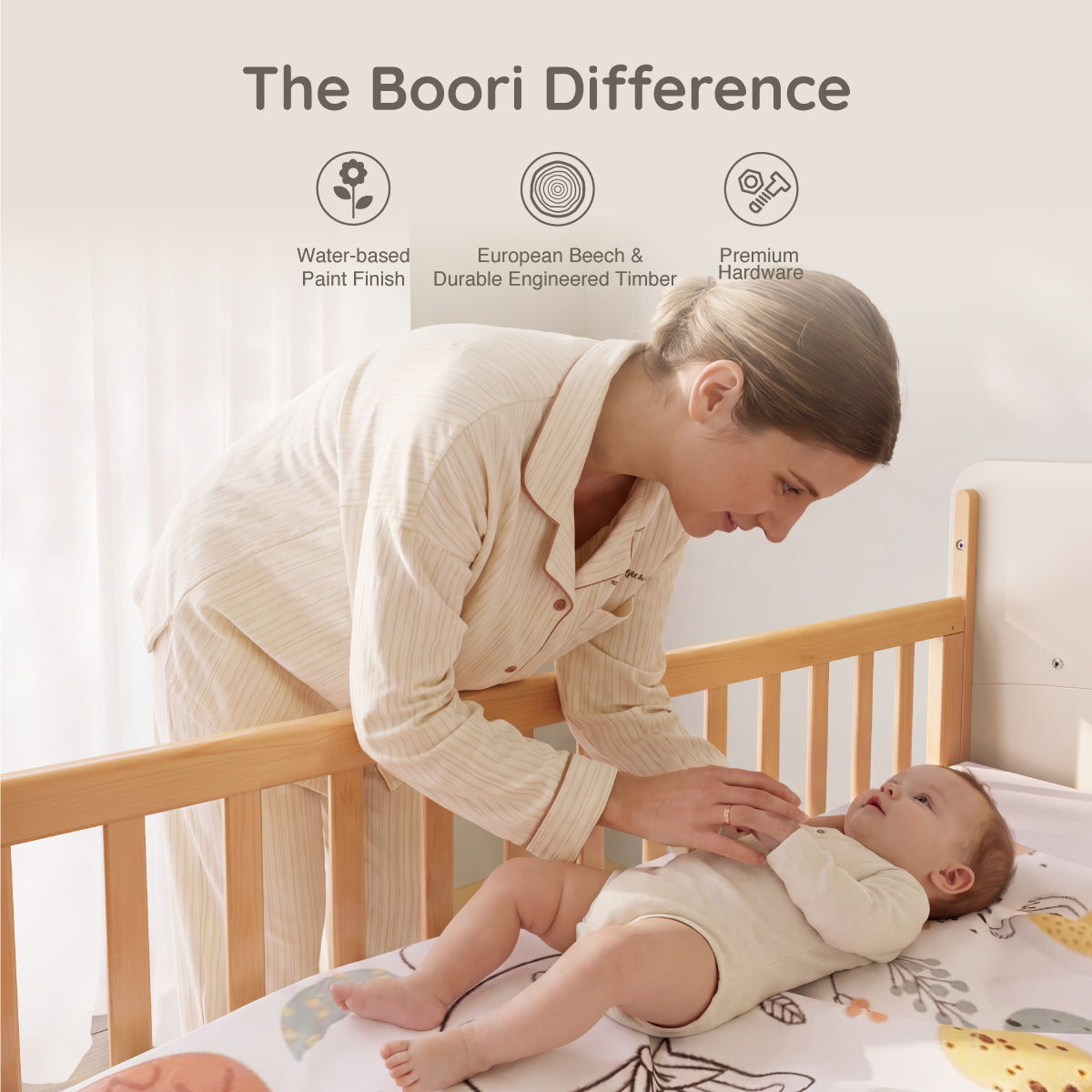 Parent changing baby in the Natty Ergonomic Cot Bed with the drop side lowered