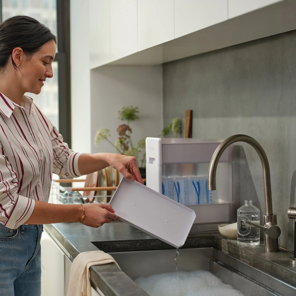 Parent using the Baby Brezza Covered Drying Rack beside the sink