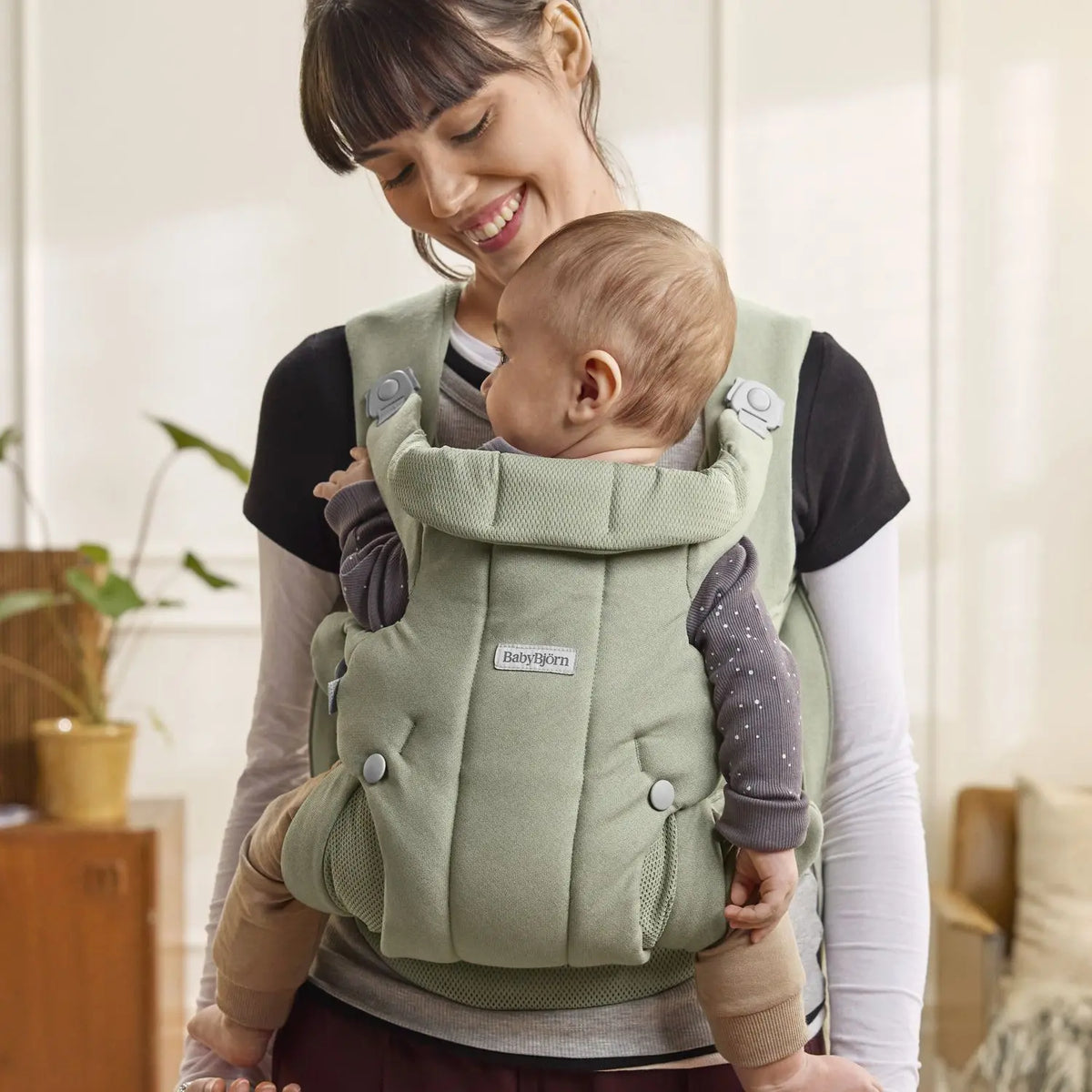 Parent wearing the BabyBjorn Baby Carrier Hold in Light Green with baby facing in