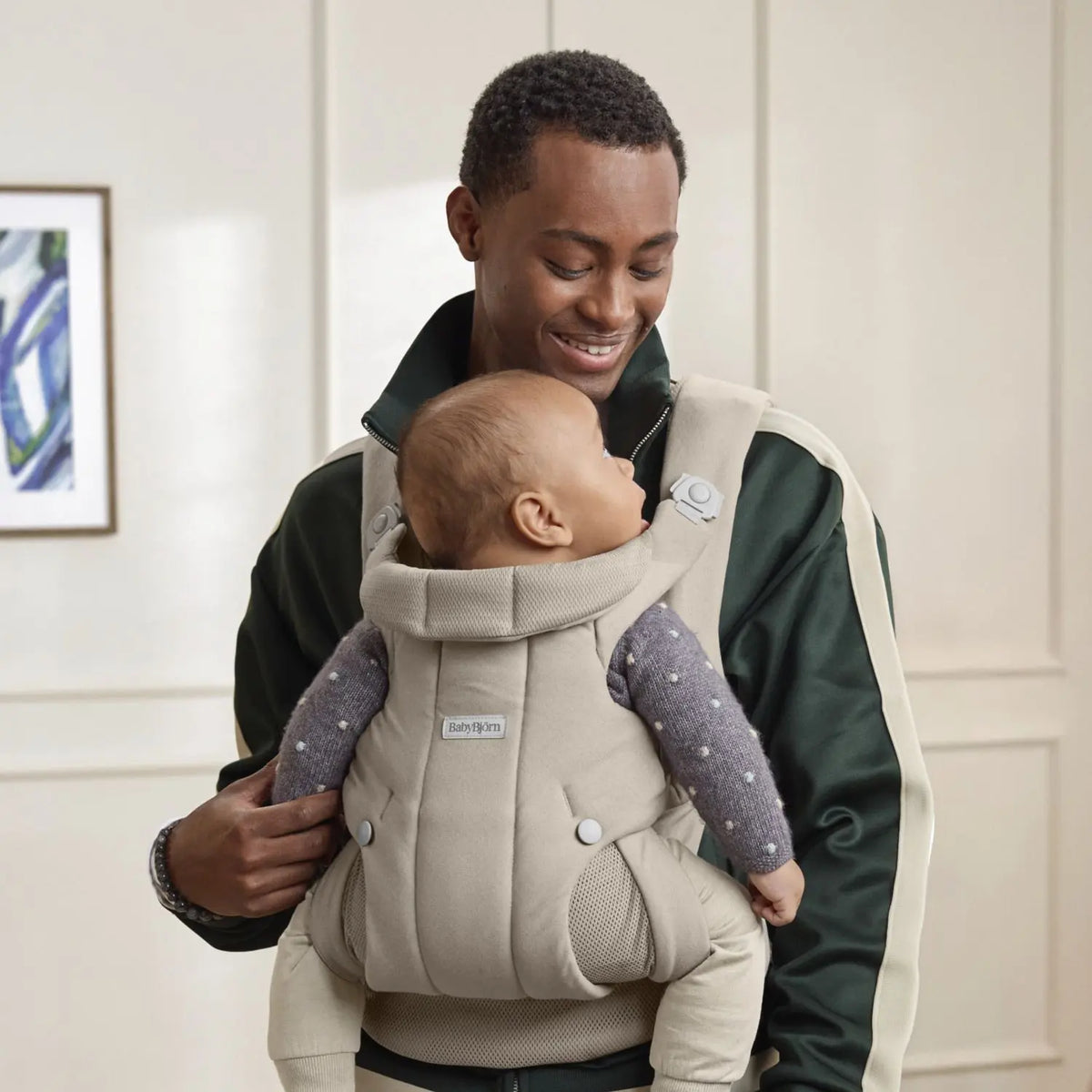 Dad wearing the BabyBjorn Baby Carrier Hold in Sand Grey with baby facing in