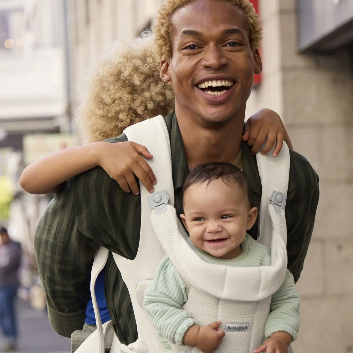 BabyBjorn Baby Carrier Hold Cream worn outdoors with a happy baby