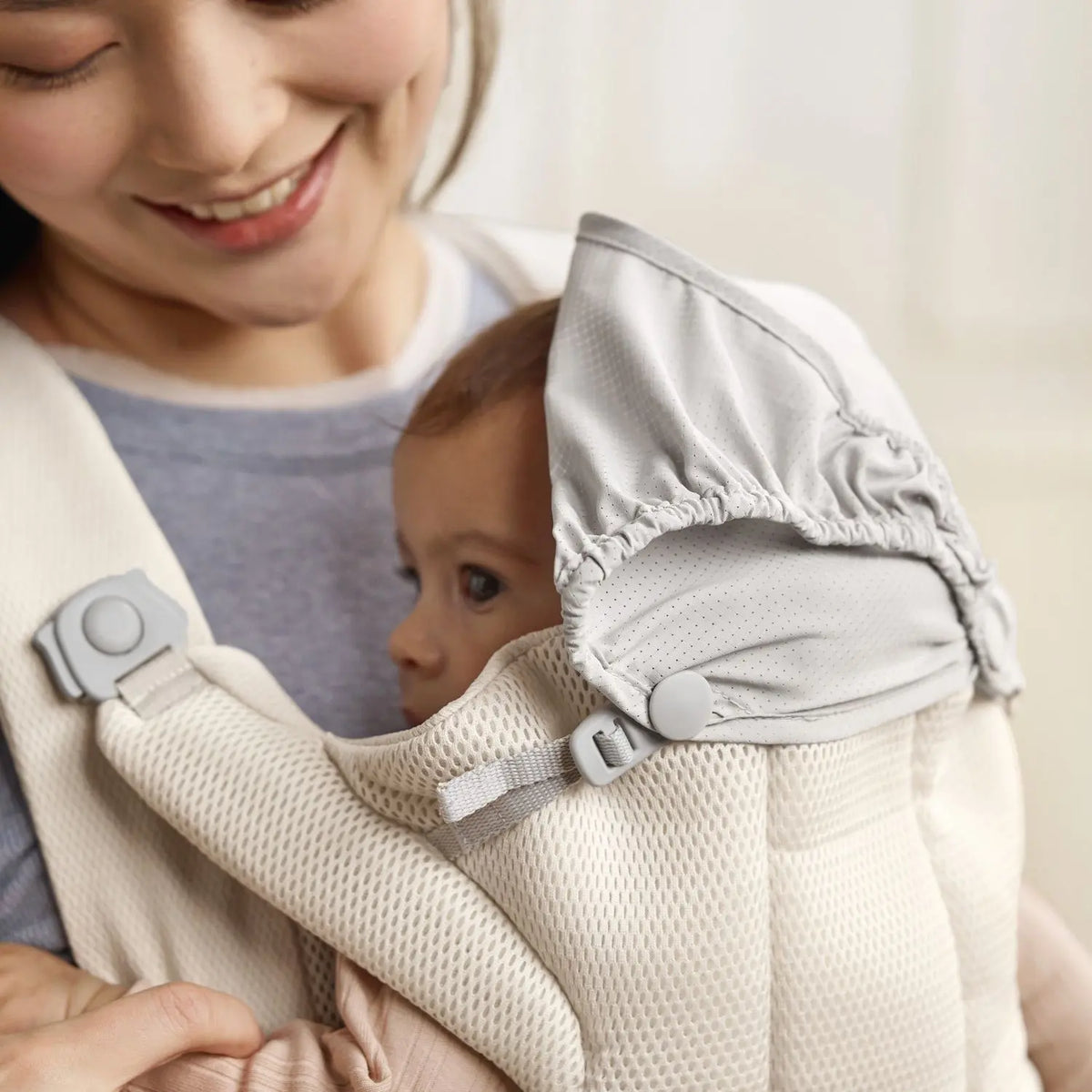 BabyBjorn Baby Carrier Hold Cream with the integrated shade over a sleeping baby