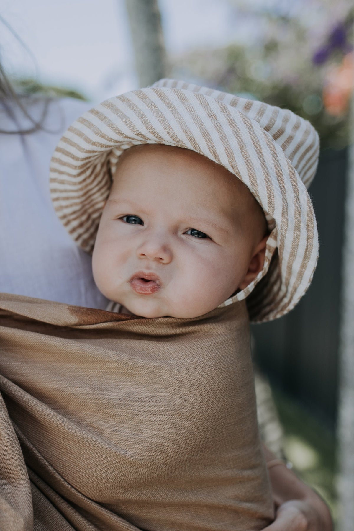 Baby wearing the Mumma Etcetera linen sun hat in Burleigh stripe with neck tie