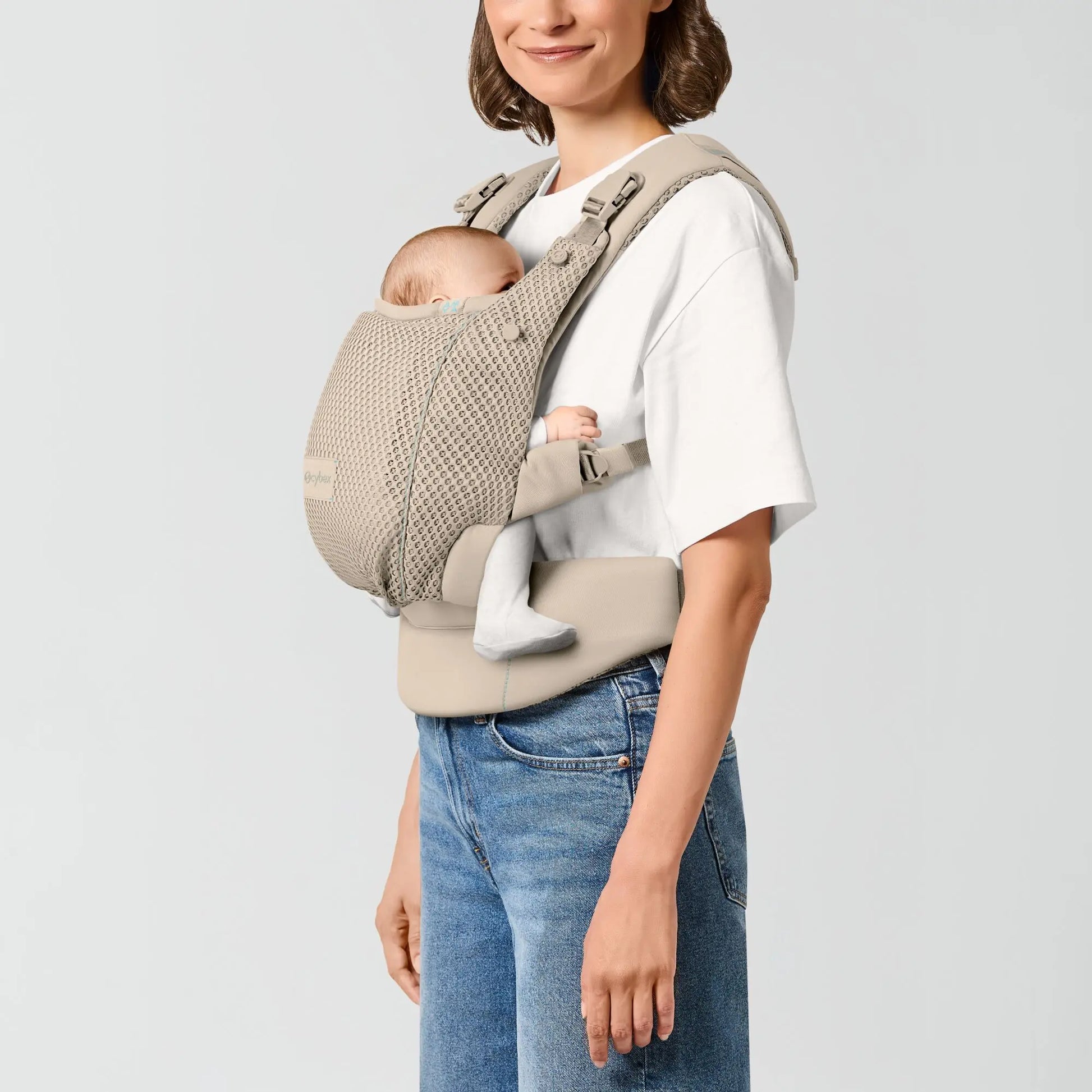 Parent carrying a newborn in the front inward position in the CYBEX Amya carrier
