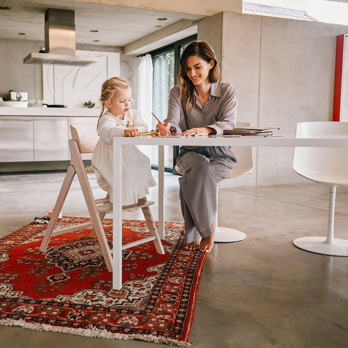 Child drawing at the family table on the Cybex Click & Fold wooden chair