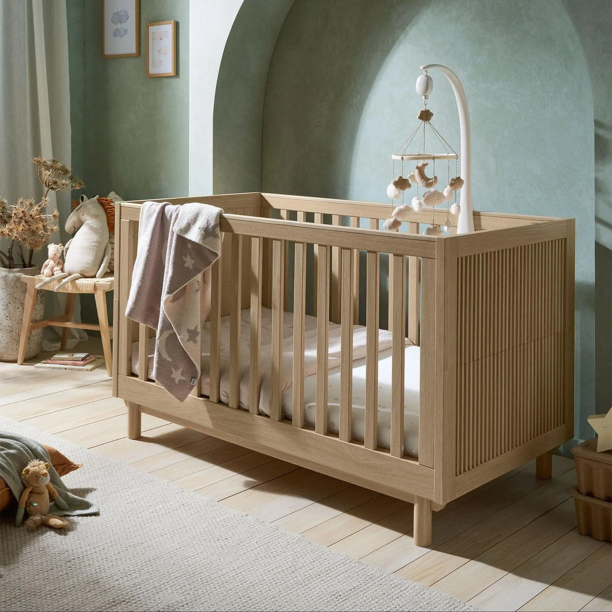 Mamas & Papas Oska Cotbed in oak with slatted sides in a nursery