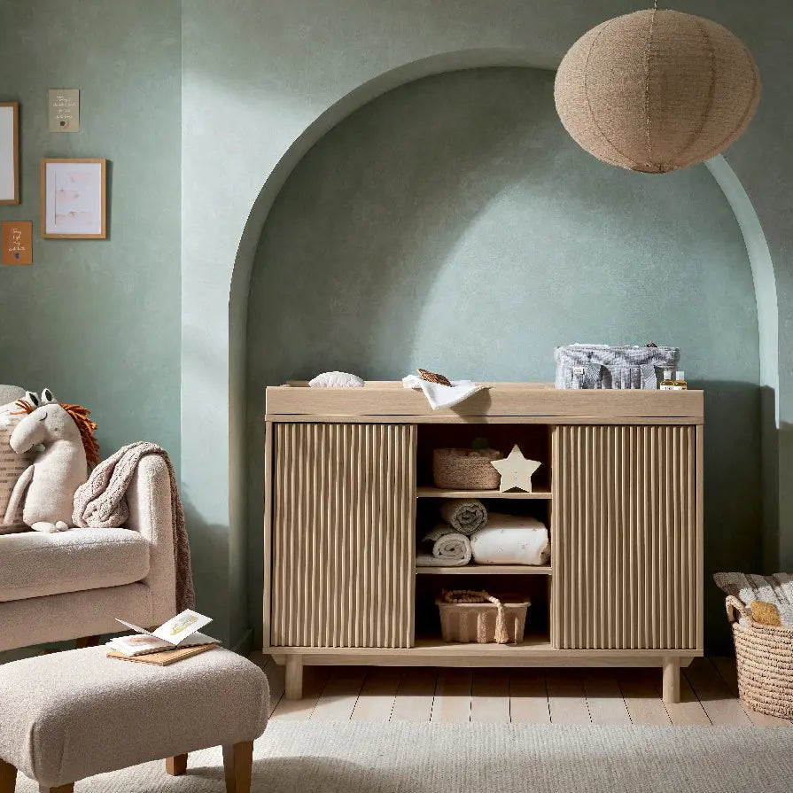 Oska wide dresser changer oak lifestyle shot with nursery styling