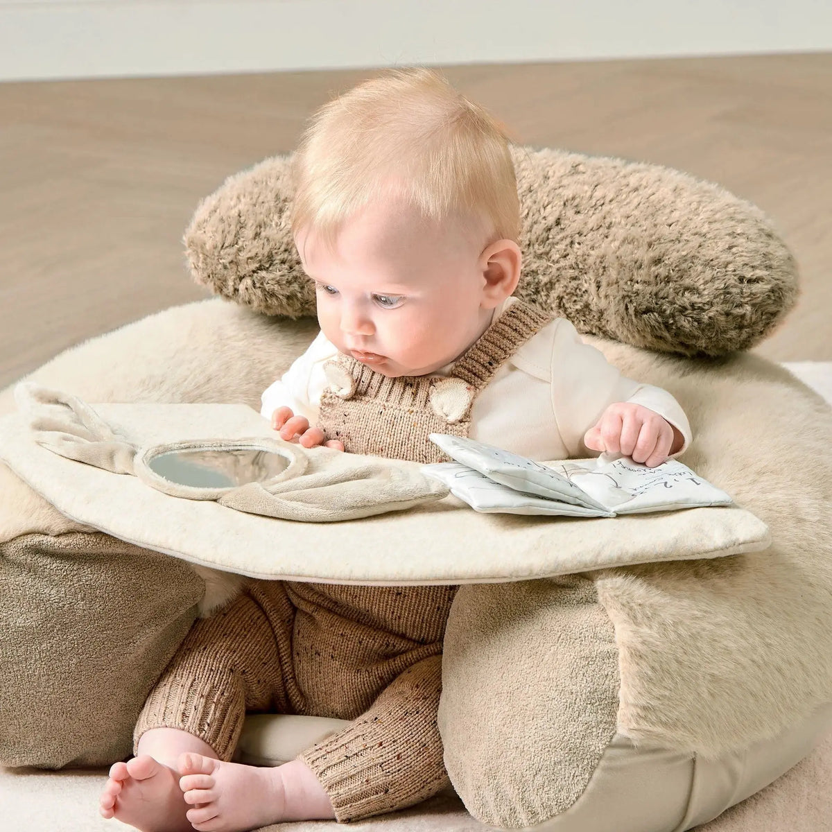 Mamas & Papas Sit & Play floor seat in Welcome to the World Millie & Boris, baby sitting in the seat reaching for the book