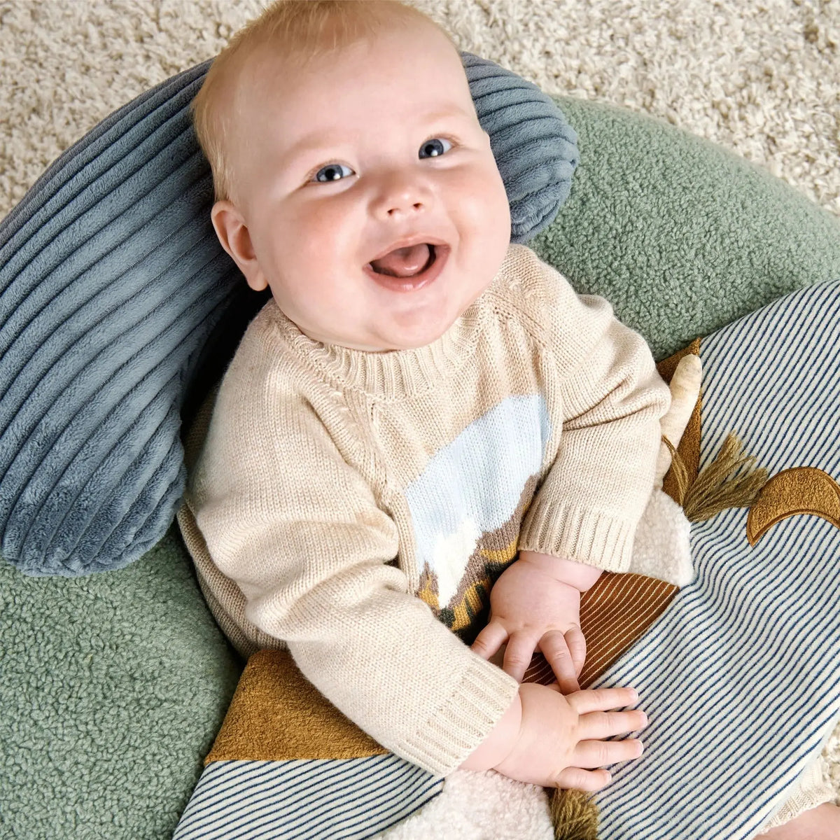 Mamas & Papas Sit & Play floor seat in Welcome to the World Pony Express, smiling baby sitting in the seat, close-up