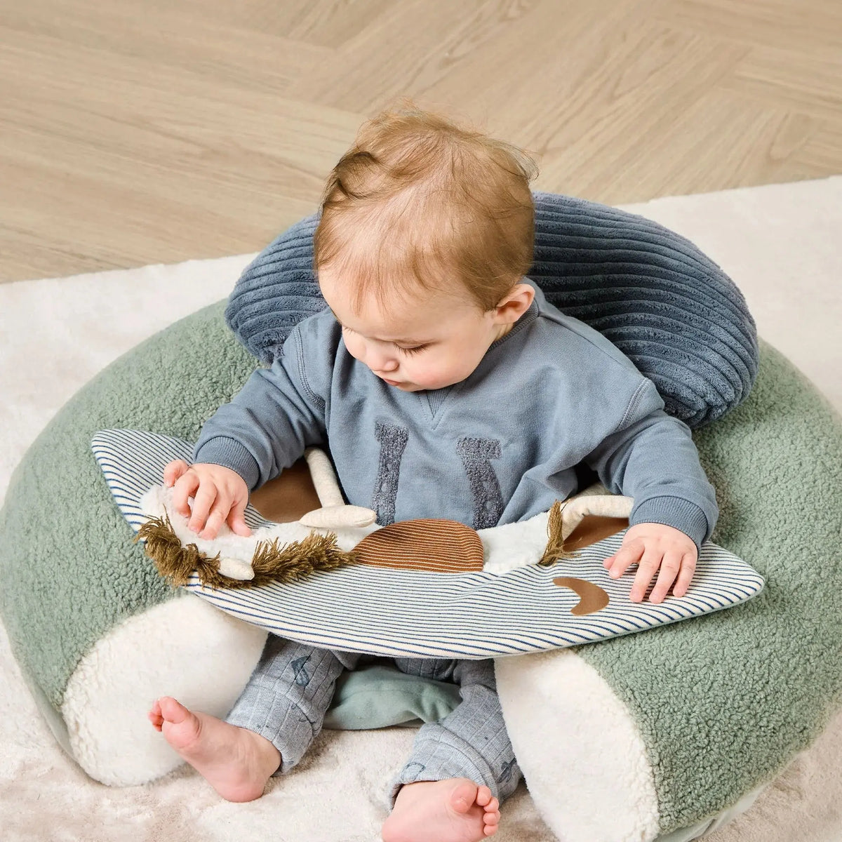 Mamas & Papas Sit & Play floor seat in Welcome to the World Pony Express, baby sitting in the seat looking down at the toys