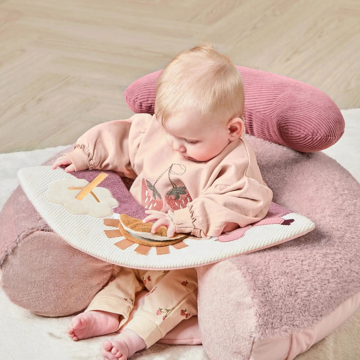 Mamas & Papas Sit & Play floor seat in Welcome to the World Floral, baby sitting in the seat looking at the toys