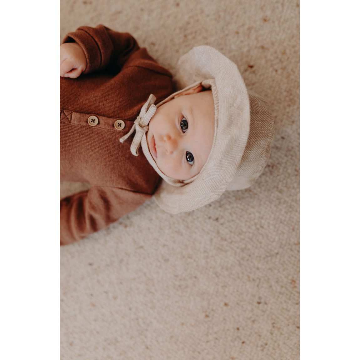 Baby wearing the Mumma Etcetera linen sun hat in Meadow with neck tie