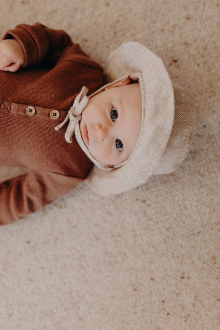Baby wearing the Mumma Etcetera linen sun hat in Meadow with neck tie