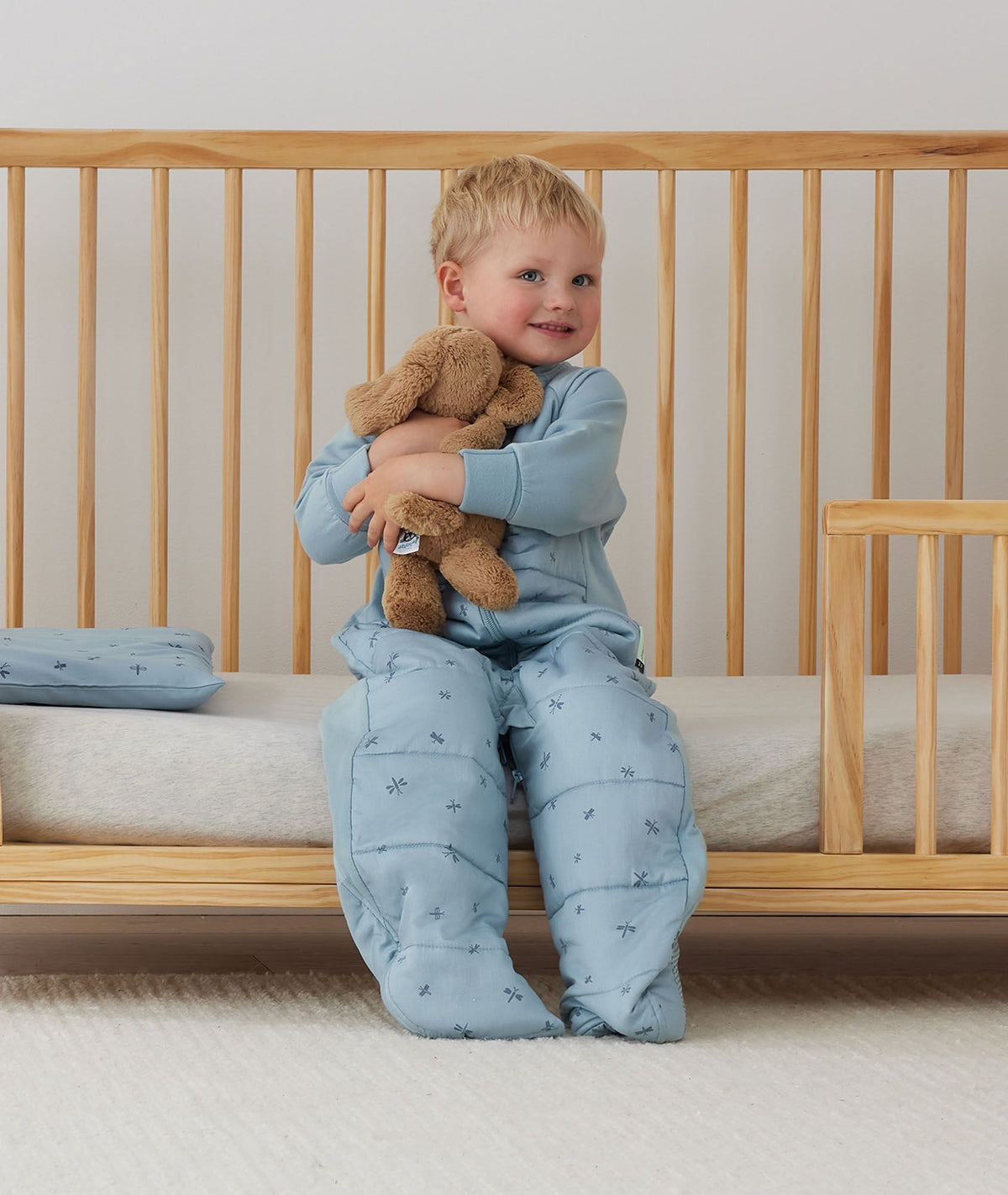 Toddler wearing the ergoPouch Sleep Suit Bag in Dragonflies, showing stretch sleeves and side panels