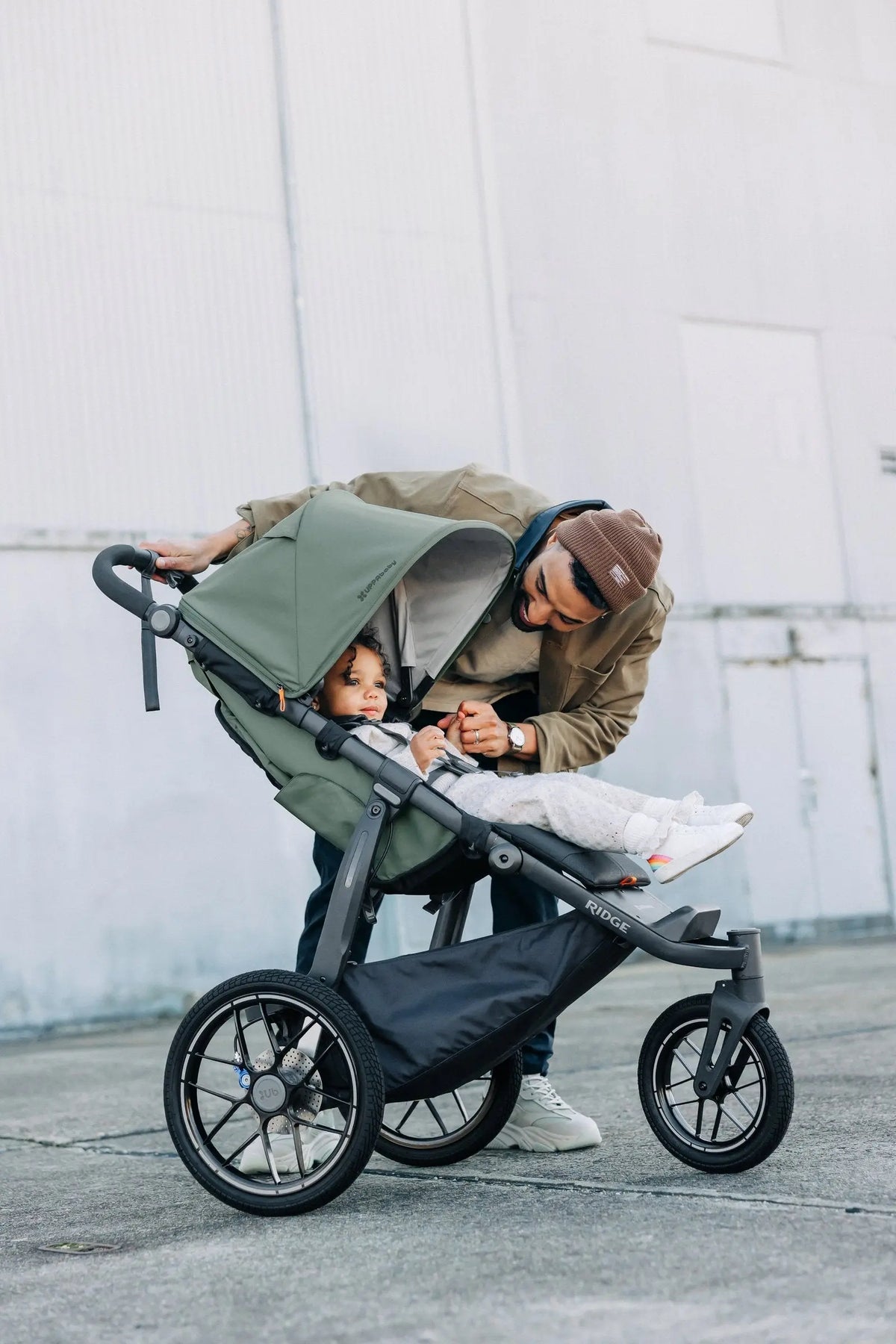 Parent checking on a toddler in the UPPAbaby Ridge V2, Evelyn (Meadow Green)