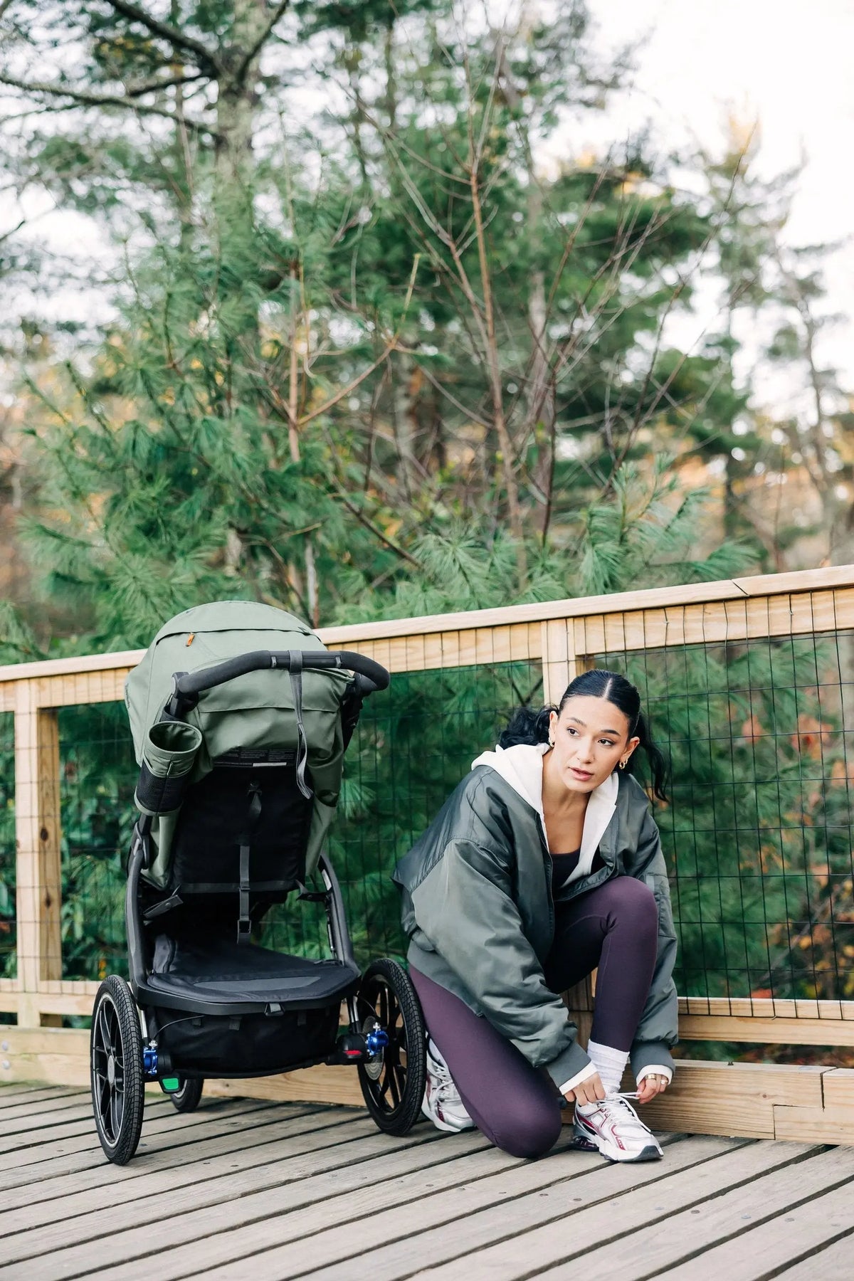 UPPAbaby Ridge V2 in Evelyn (Meadow Green) parked on a boardwalk while a parent ties her shoe before a run