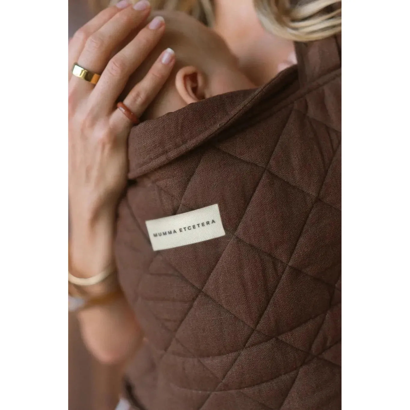 Close-up of diamond quilting and linen weave on the Coco Daily Carrier, brand label at centre
