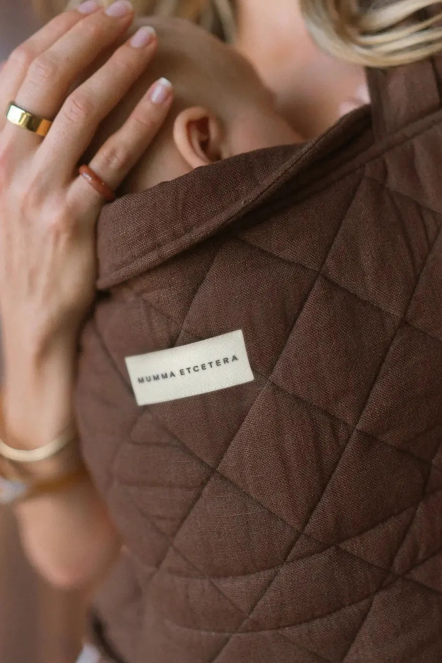 Close-up of diamond quilting and linen weave on the Coco Daily Carrier, brand label at centre