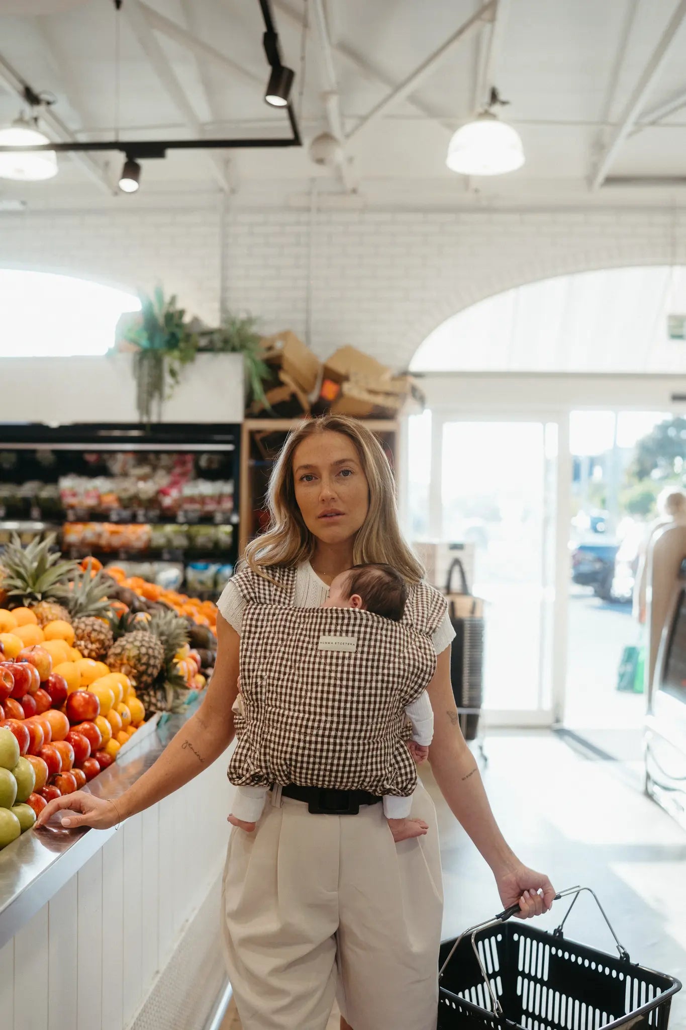 Parent wearing the Elston gingham Daily Carrier, front inward-facing carry