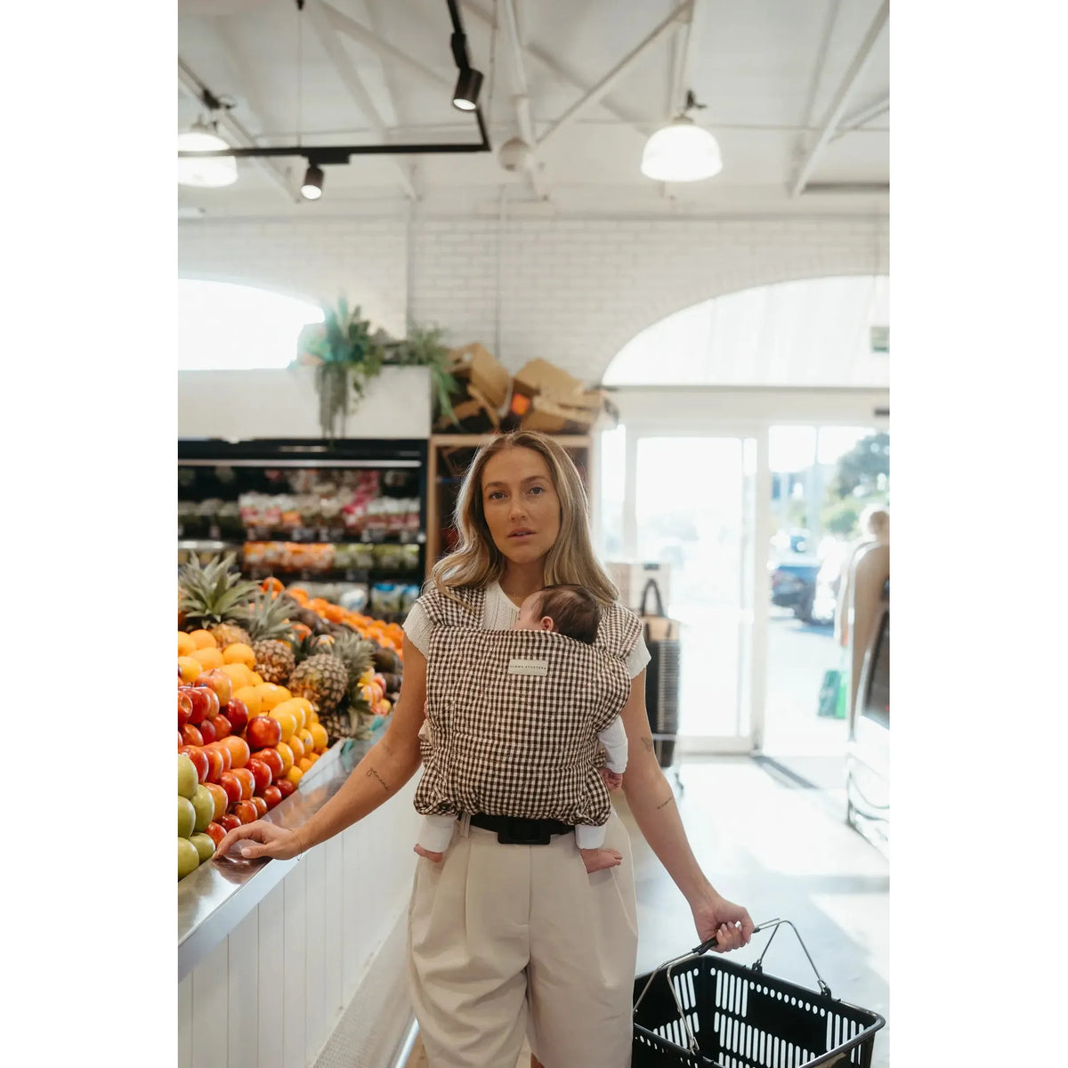 Parent wearing the Elston gingham Daily Carrier, front inward-facing carry