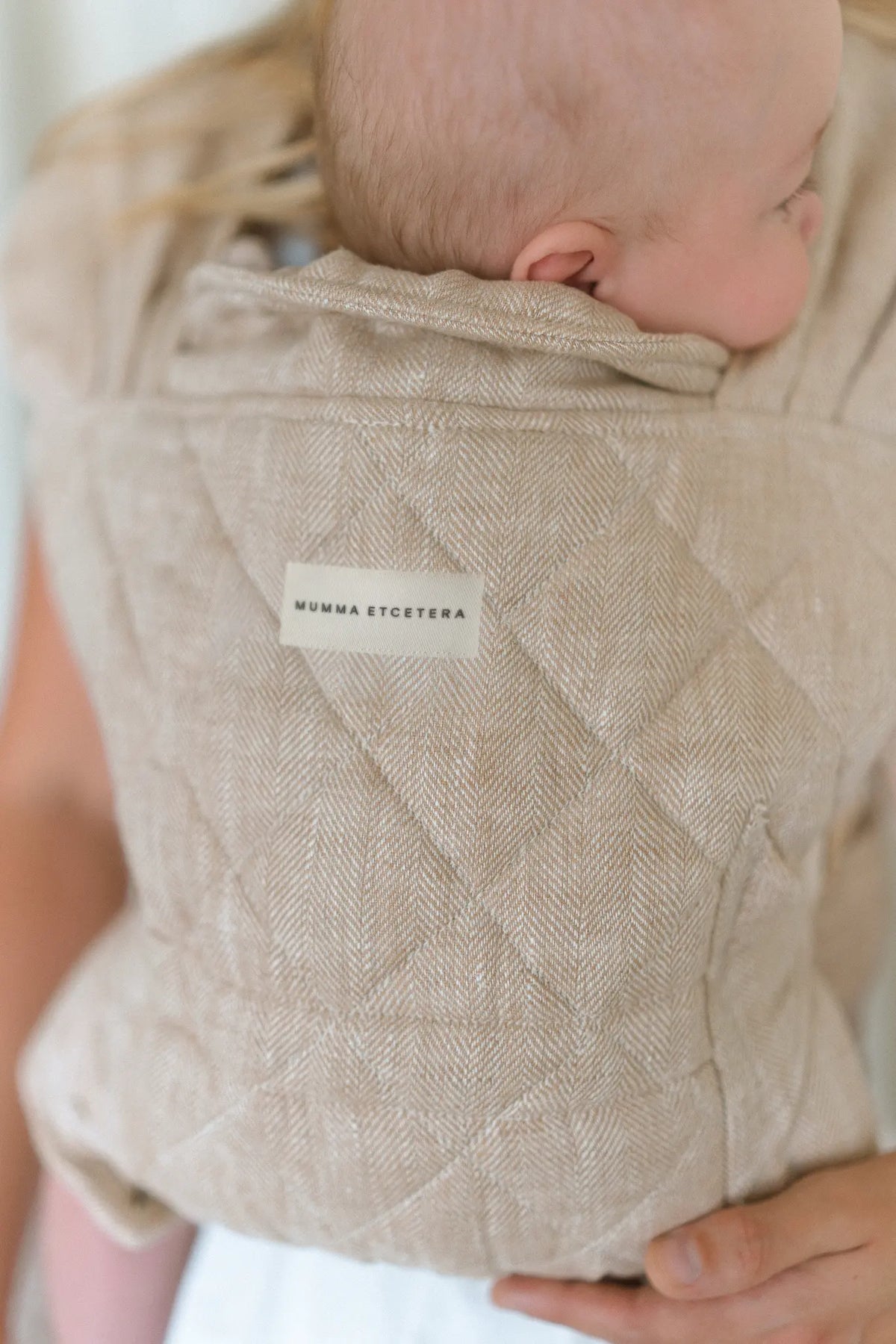 Mumma Etcetera label on the Meadow linen Daily Carrier, baby settled against the quilted panel