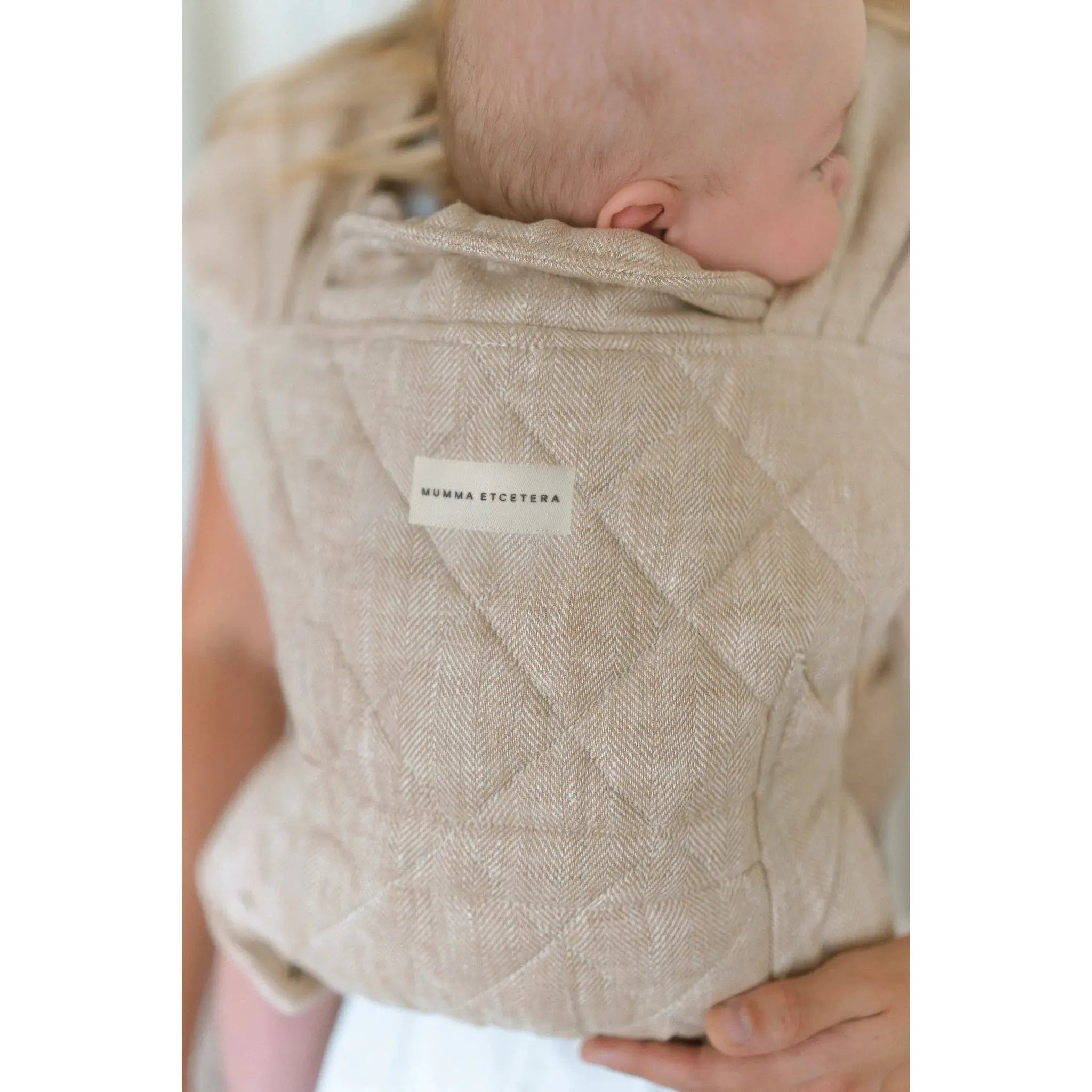Mumma Etcetera label on the Meadow linen Daily Carrier, baby settled against the quilted panel