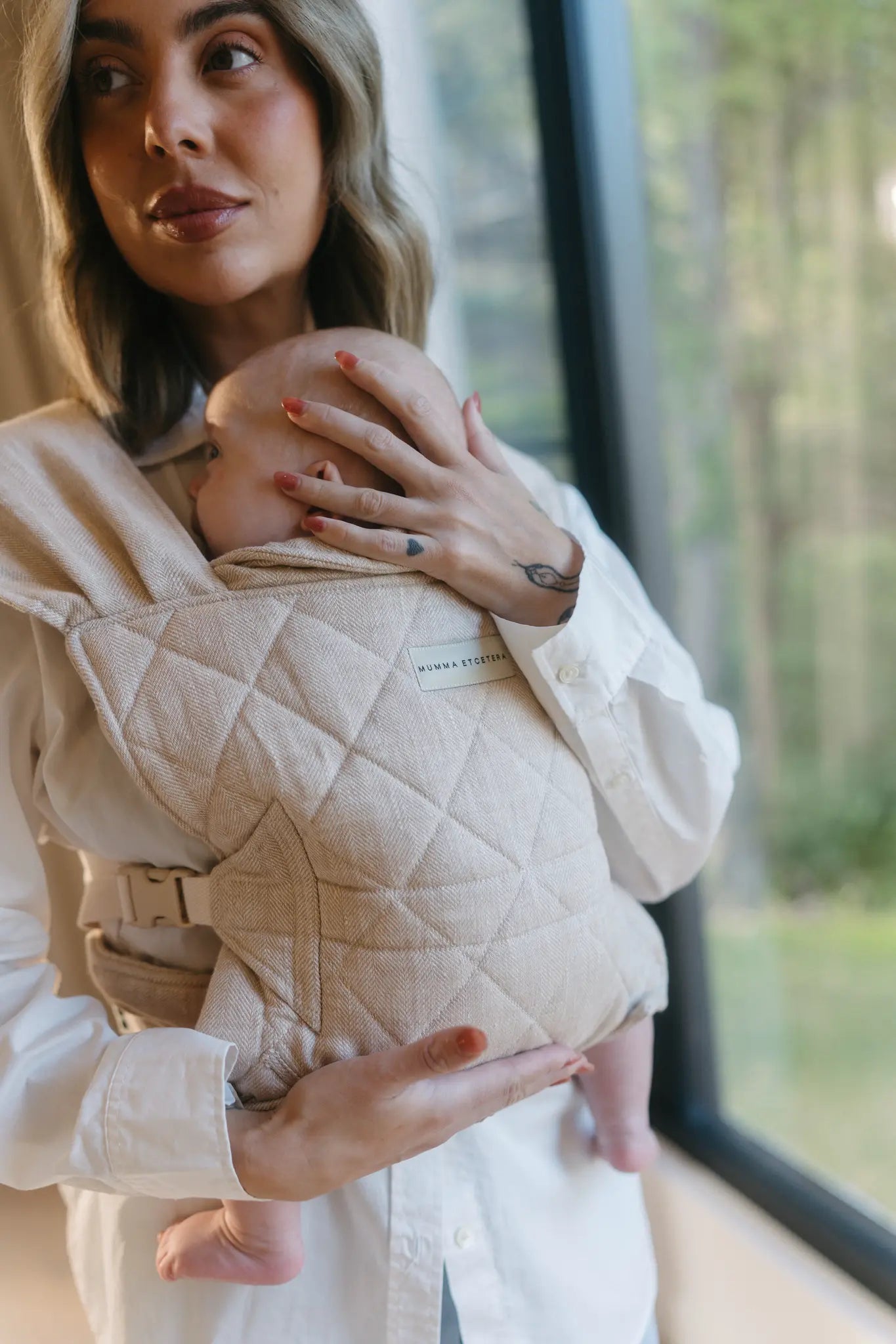 Parent wearing newborn in the Meadow oatmeal linen Daily Carrier