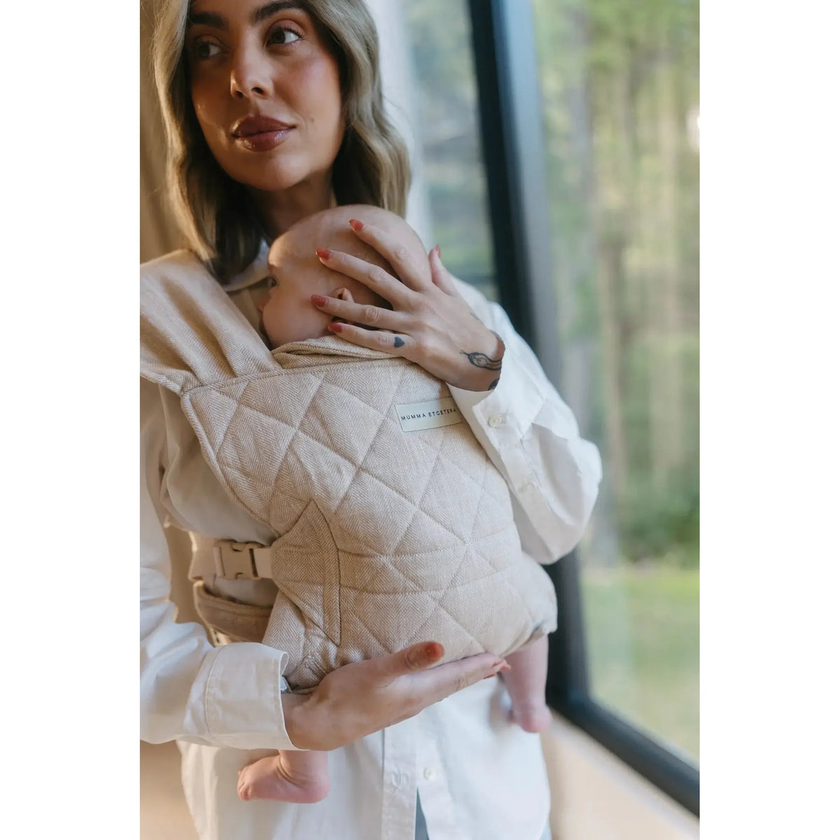 Parent wearing newborn in the Meadow oatmeal linen Daily Carrier