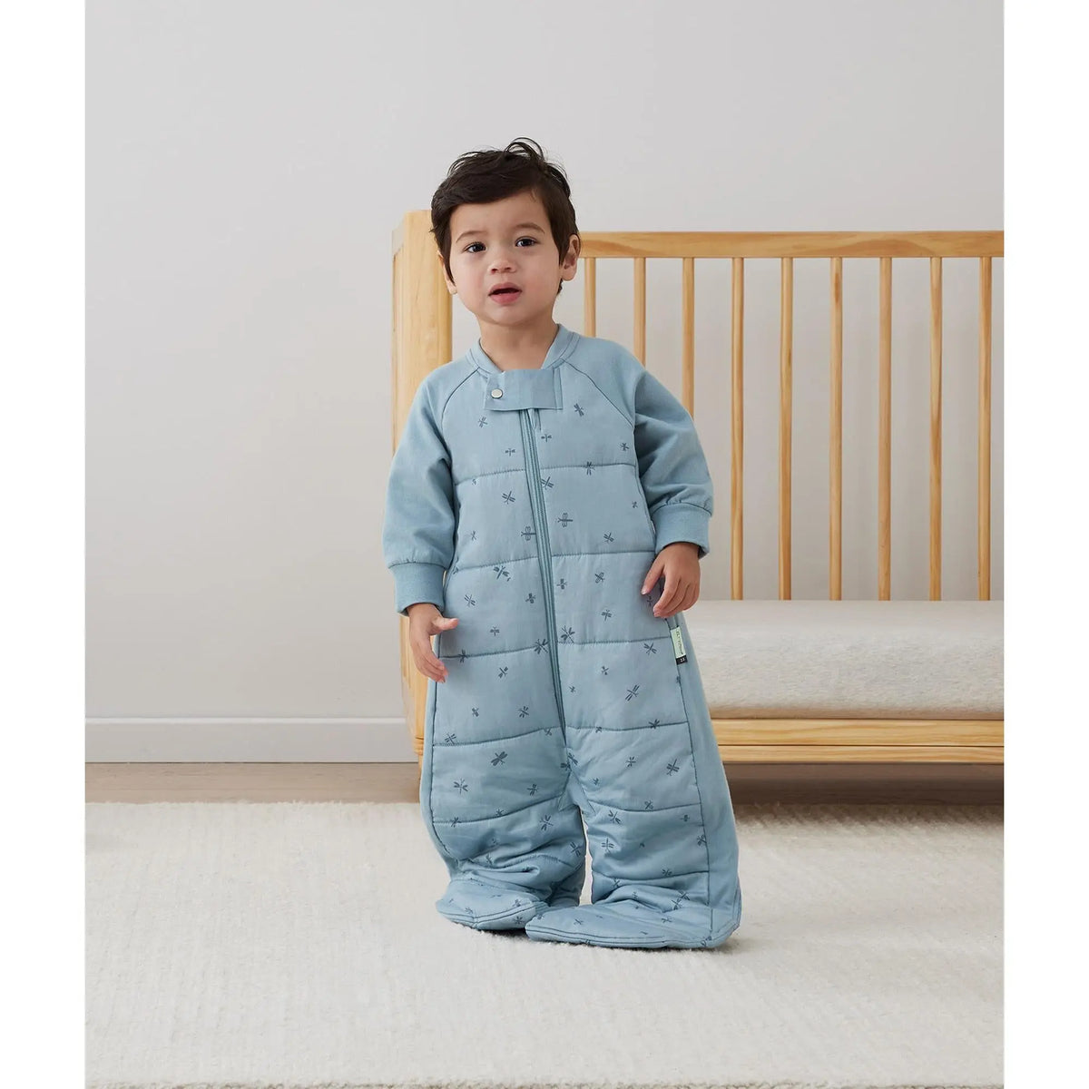 Toddler standing in the ergoPouch Sleep Suit Bag 2.5 TOG Dragonflies with legs unzipped