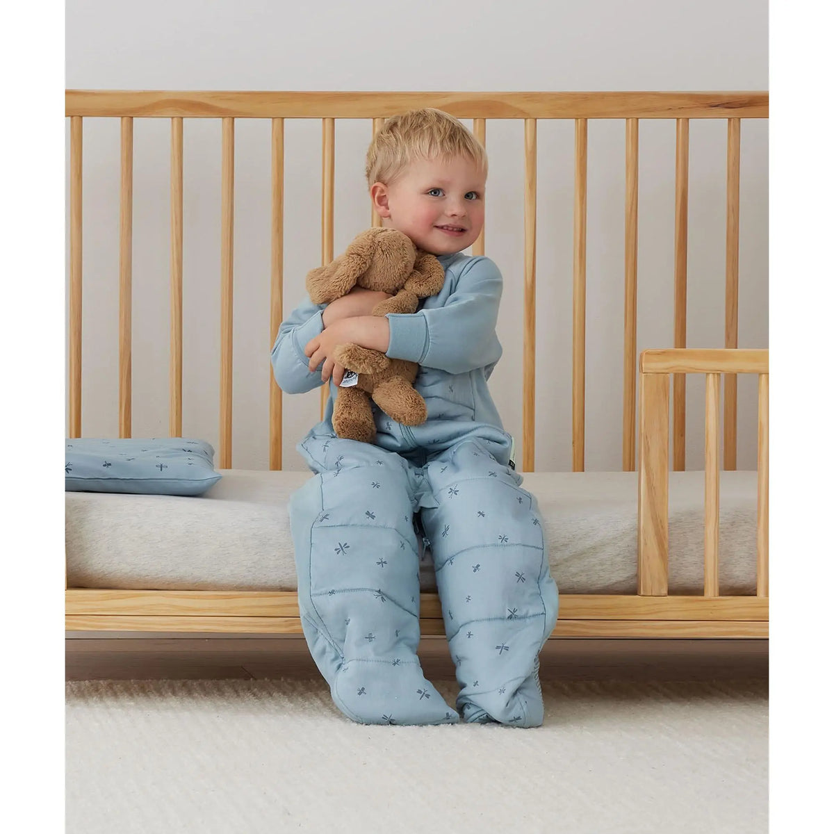 Toddler wearing the ergoPouch Sleep Suit Bag in Dragonflies, showing stretch sleeves and side panels