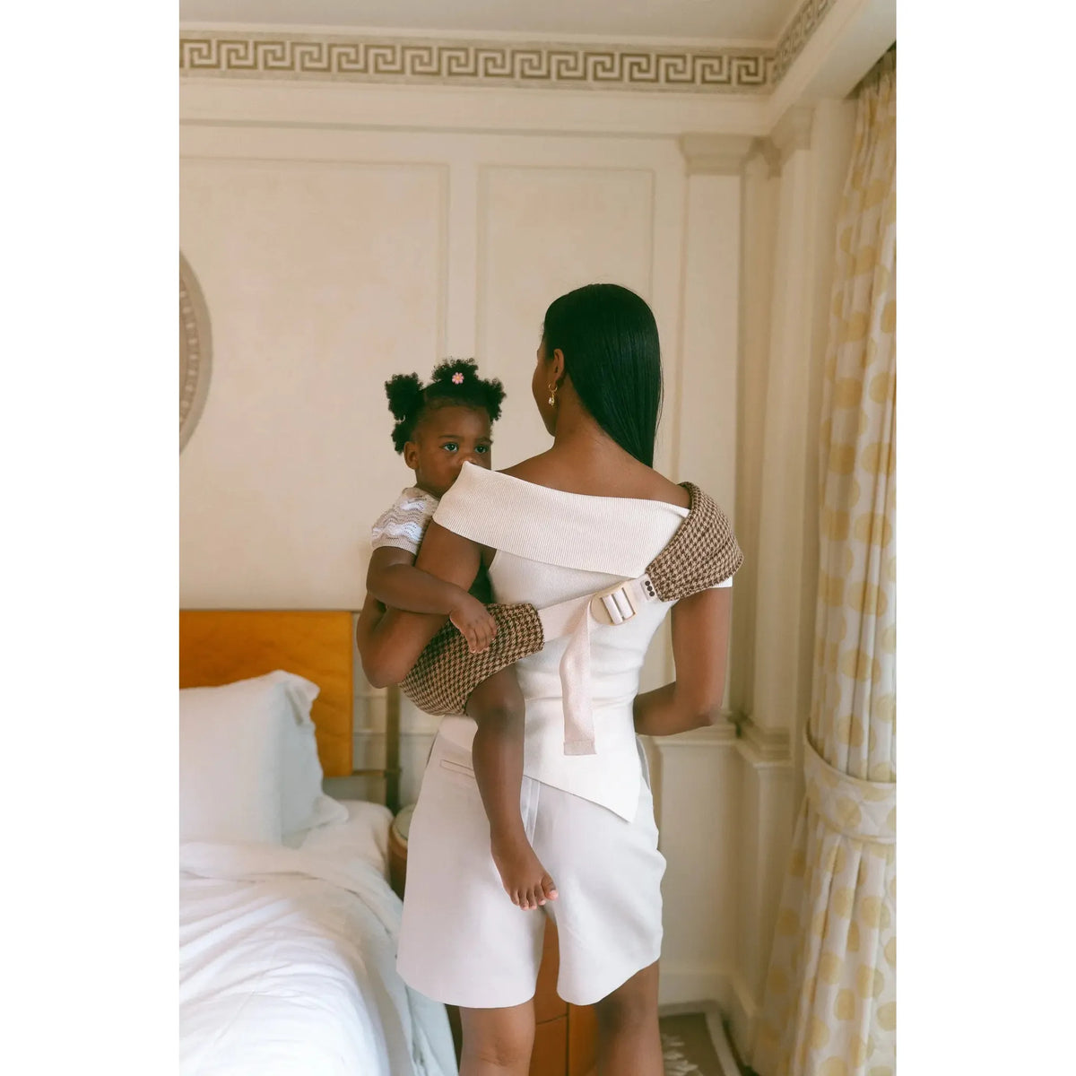 Back view of the Arista houndstooth Hipsy toddler carrier, wide strap running across mum's shoulder