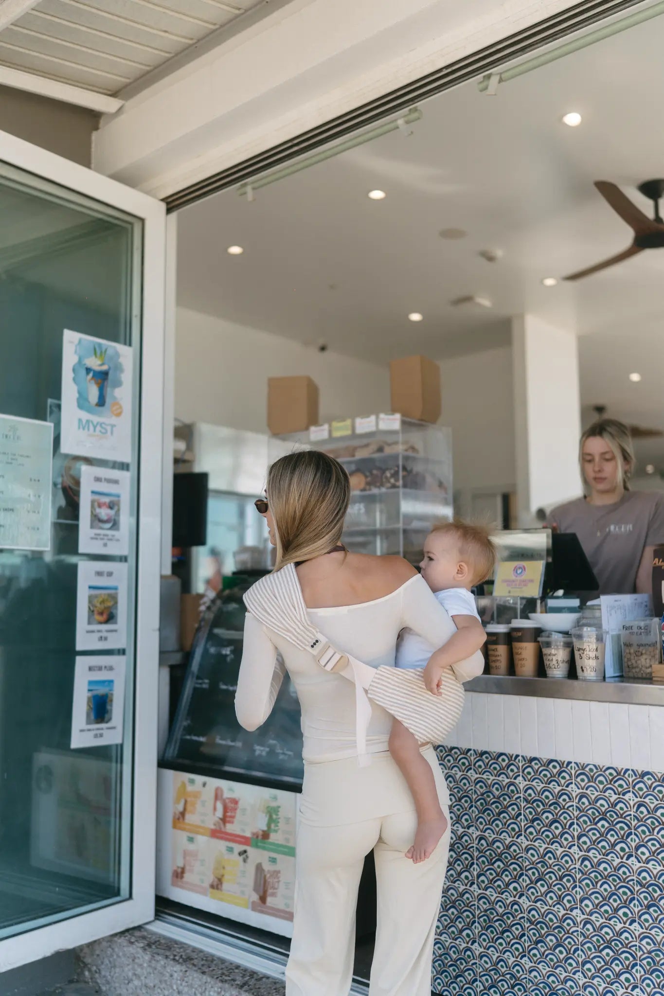 Mum wearing the Burleigh stripe Hipsy Carrier with toddler on her hip