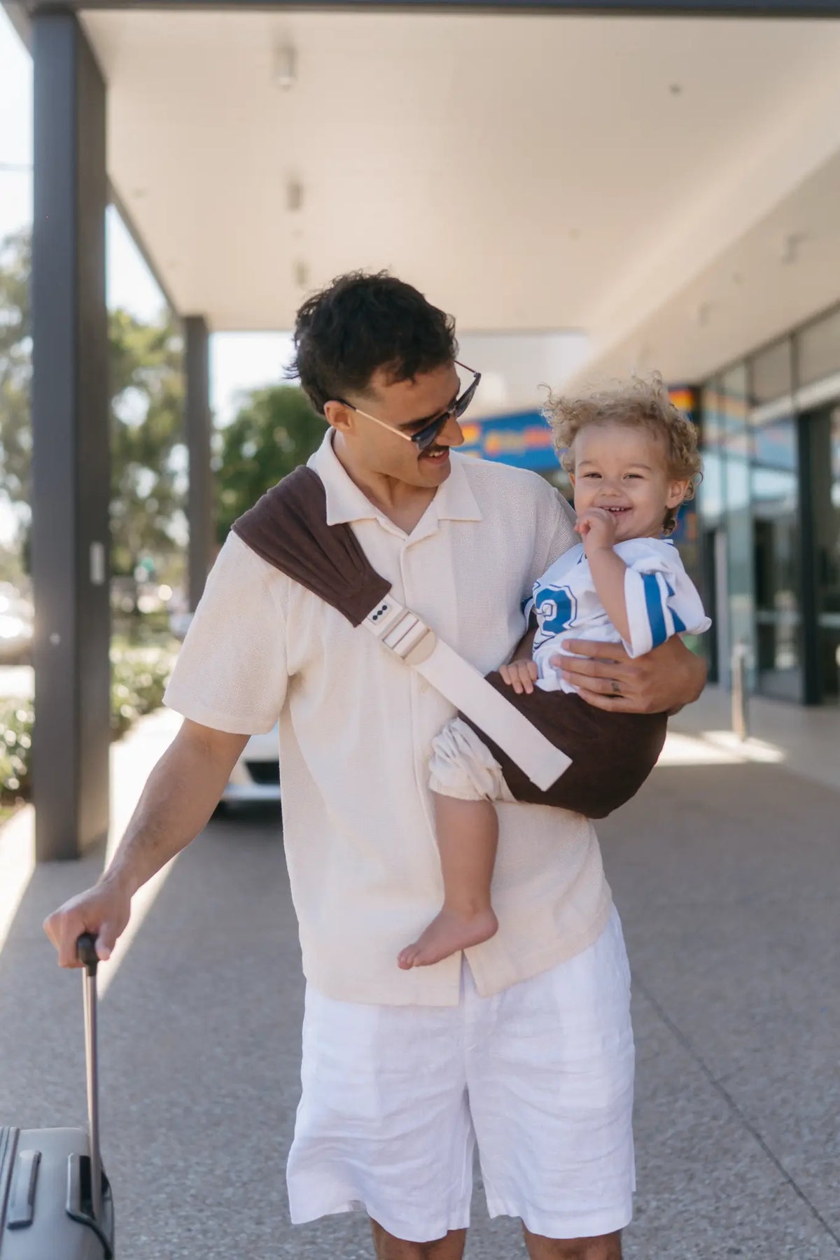 Coco linen Hipsy hip carrier worn, showing quilted seat supporting toddler