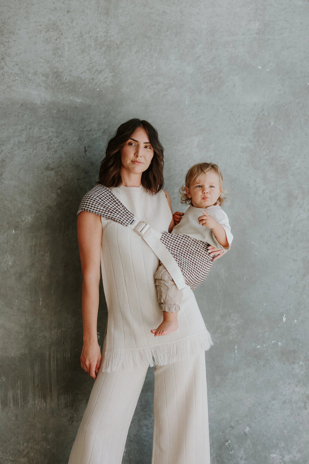 Mum carries toddler on her hip in the Elston gingham Mumma Etcetera Hipsy Carrier