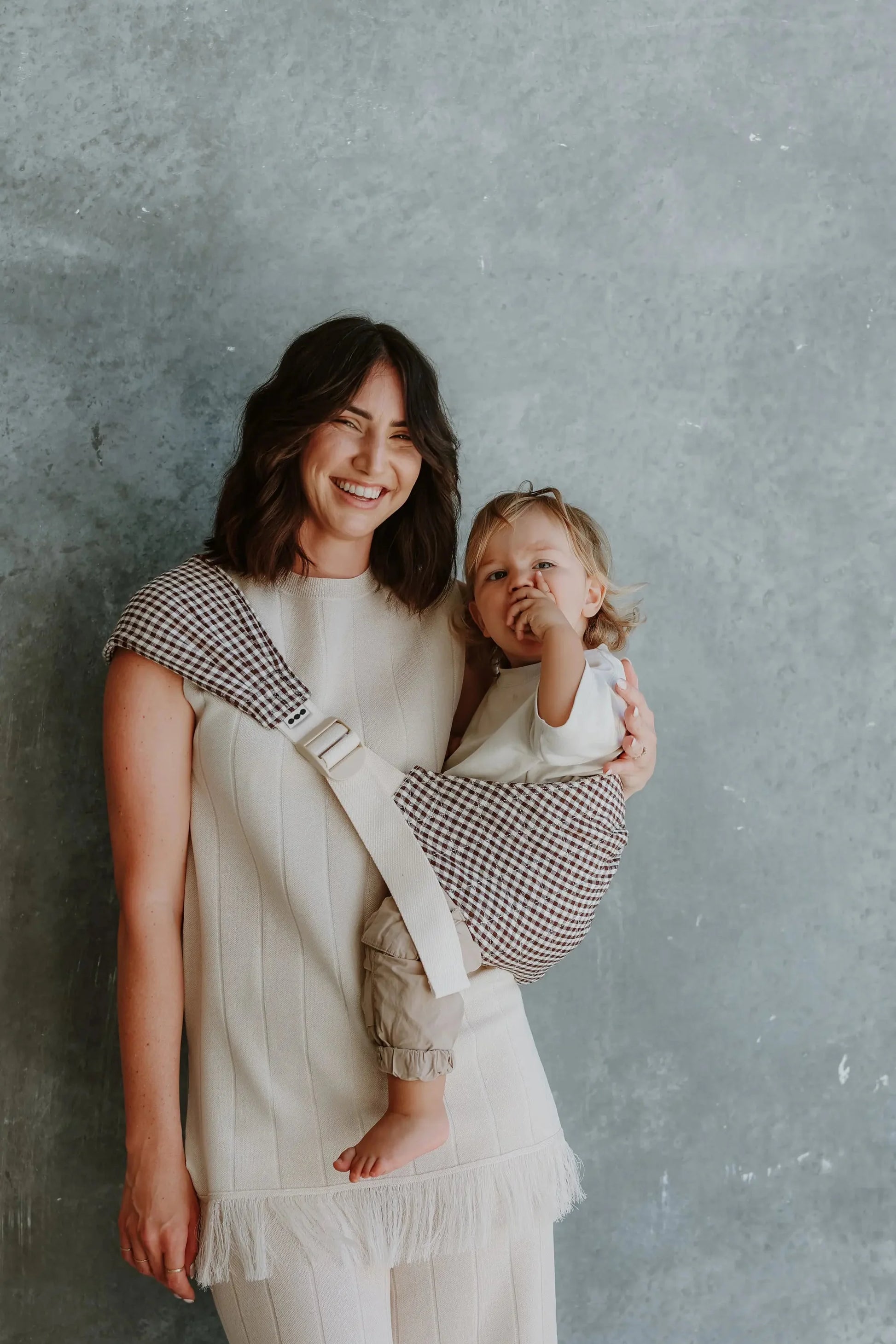 Elston gingham Hipsy hip carrier worn, showing quilted linen seat supporting toddler