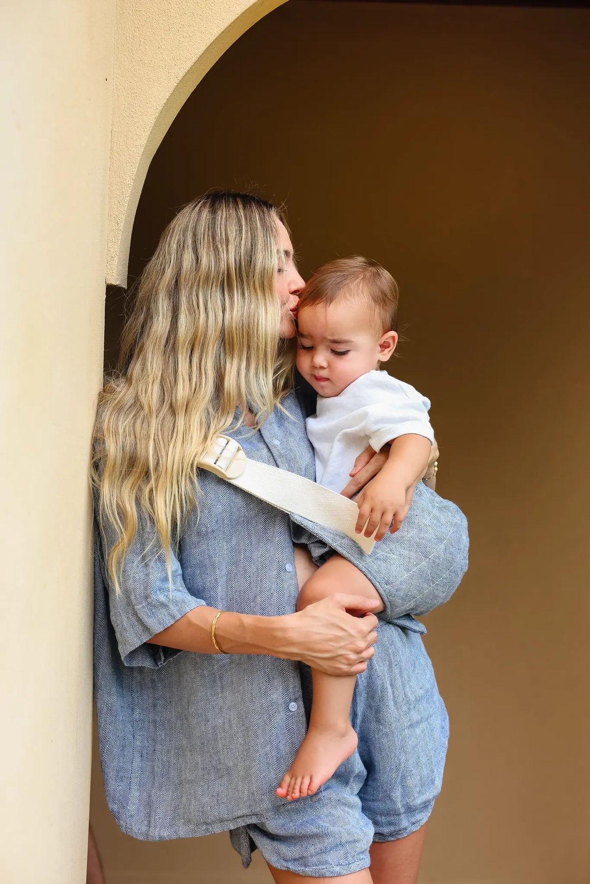 Mum kisses her toddler's head, both arms around him in the Lane Hipsy hip carrier