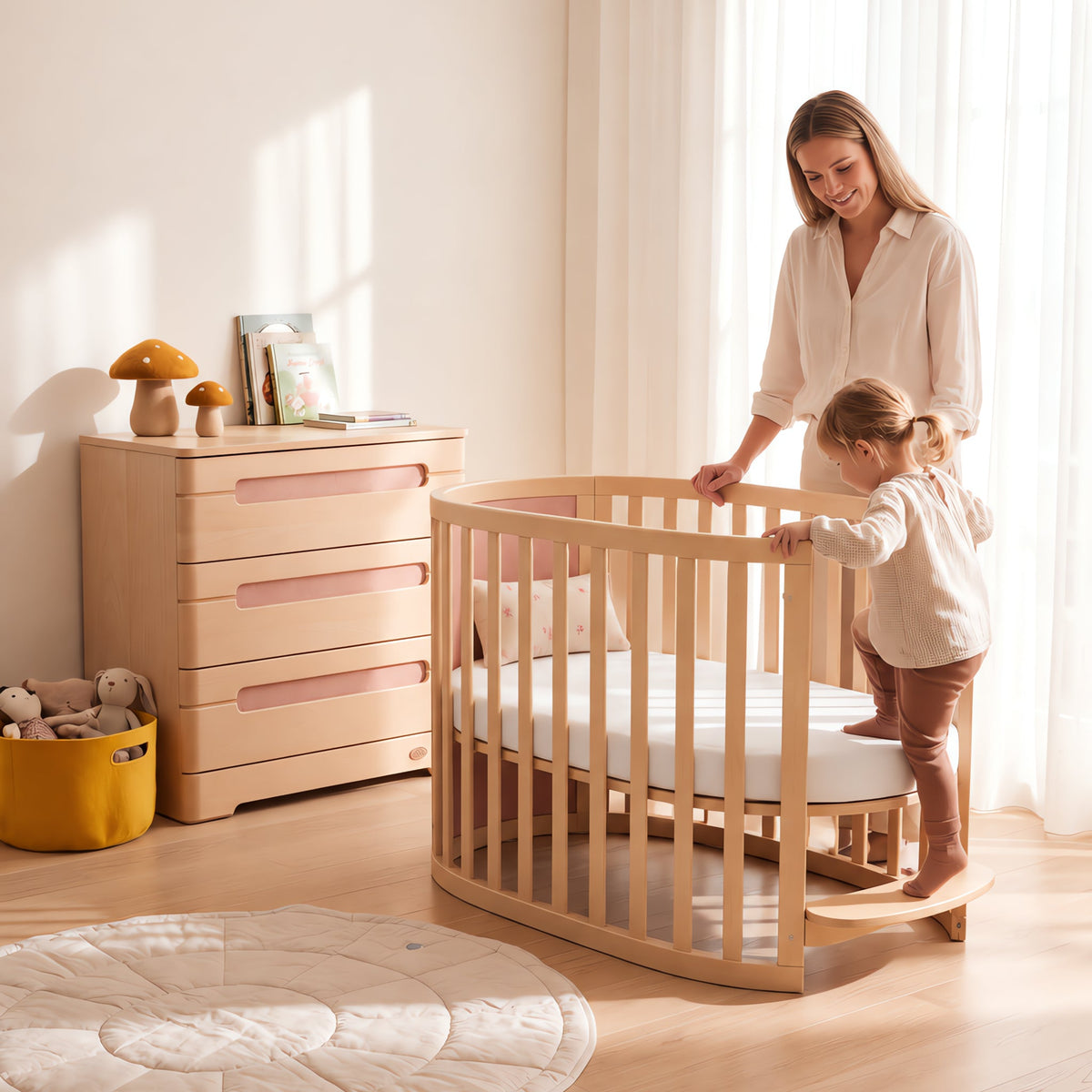 Parent lifting baby from the Eden Elite Oval Cot (shown in Cherry & Beech)