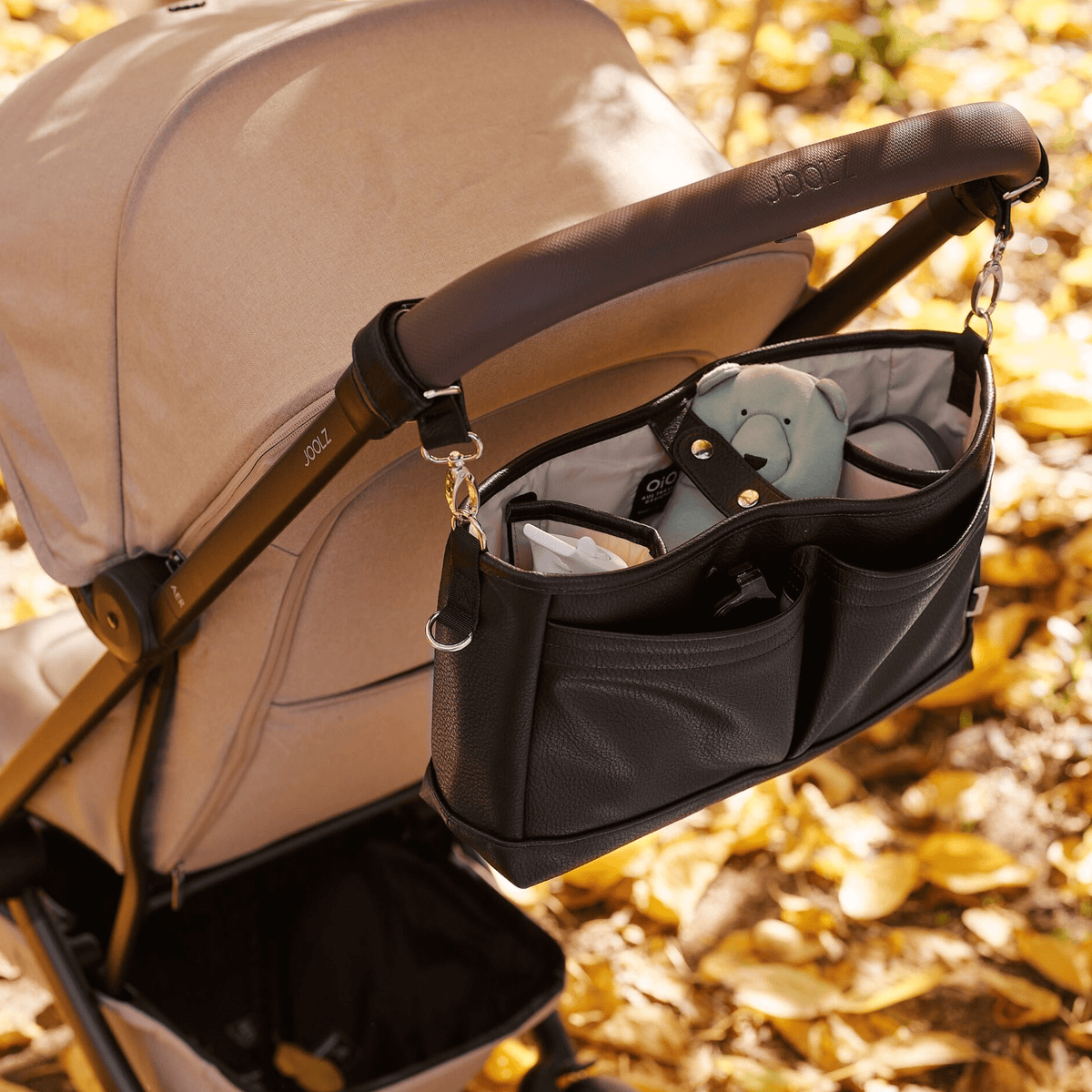 OiOi Signature Pram Caddy black vegan leather shown in use on a stroller