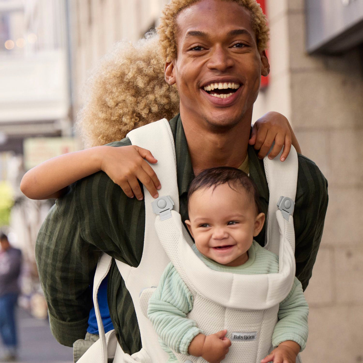 BabyBjorn Baby Carrier Hold Cream worn outdoors with a happy baby