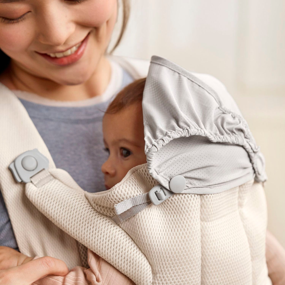BabyBjorn Baby Carrier Hold Cream with the integrated shade over a sleeping baby