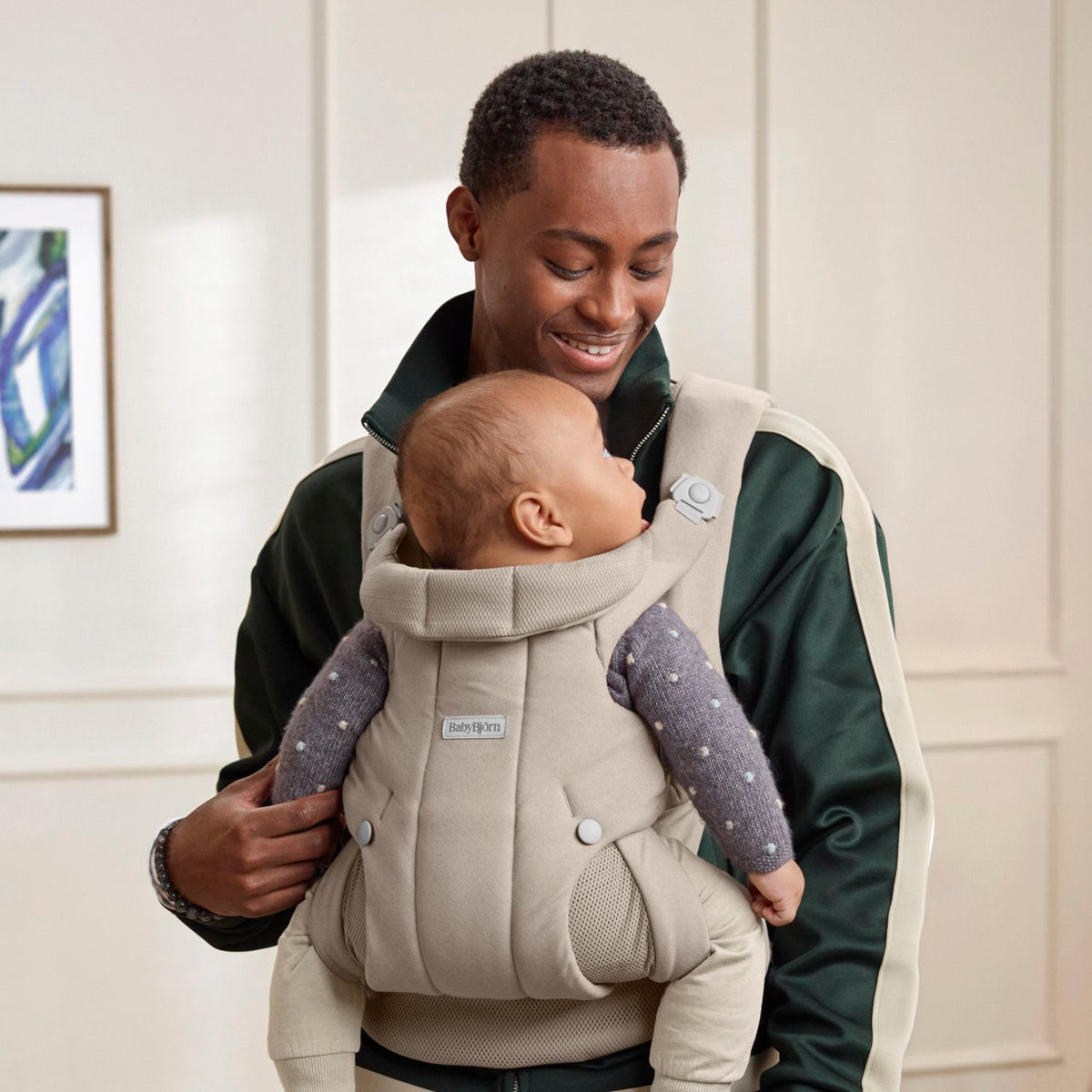 Dad wearing the BabyBjorn Baby Carrier Hold in Sand Grey with baby facing in