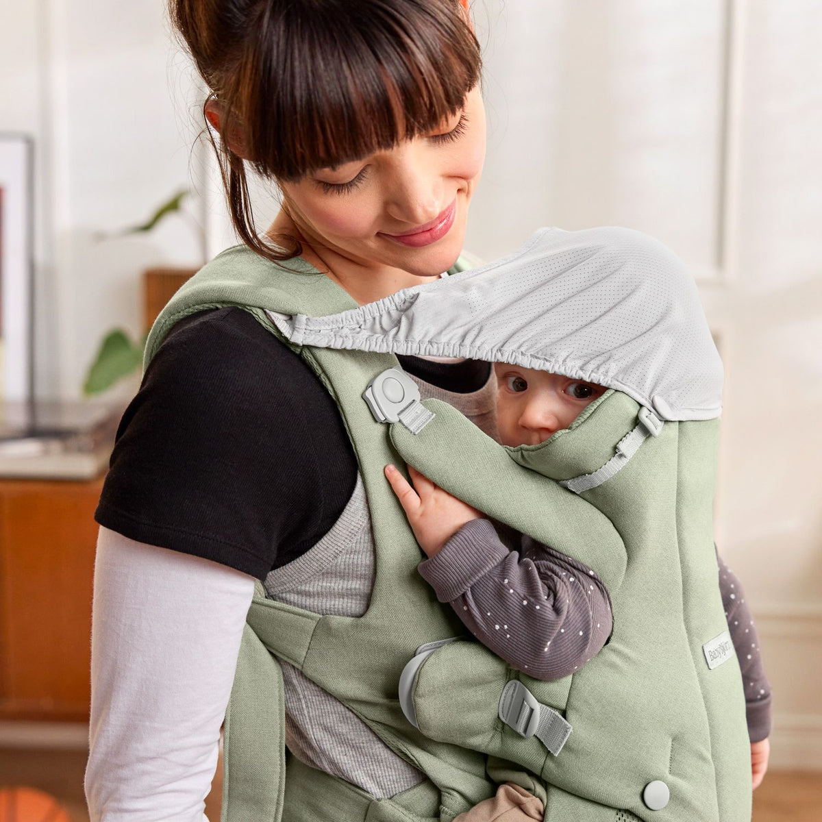 BabyBjorn Baby Carrier Hold Light Green with the integrated shade up for a nap