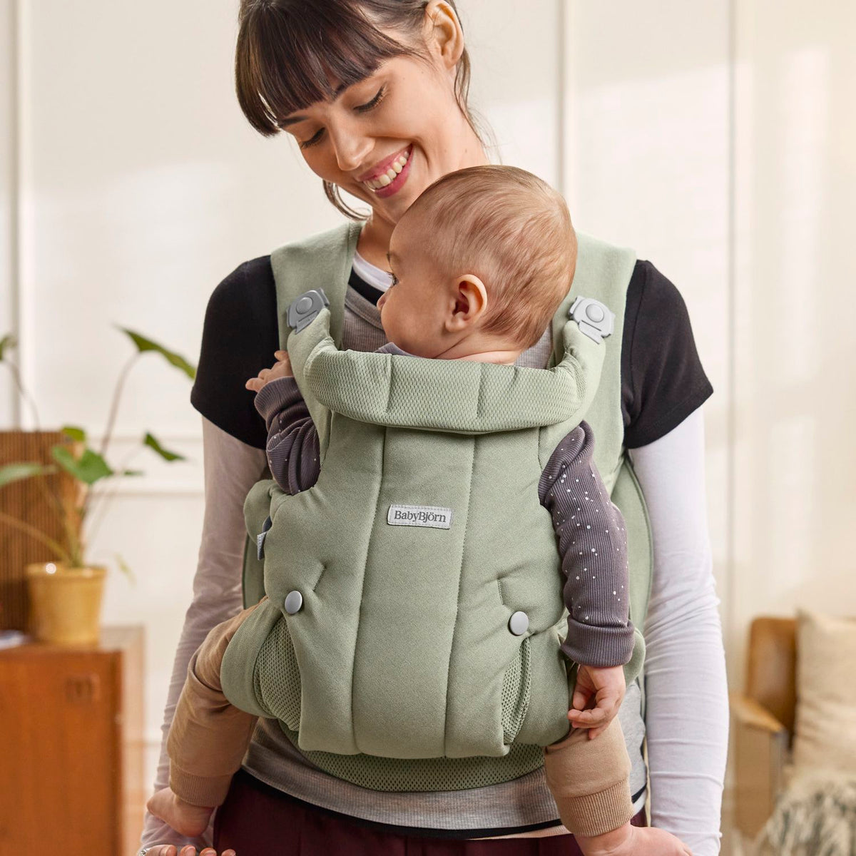 Parent wearing the BabyBjorn Baby Carrier Hold in Light Green with baby facing in